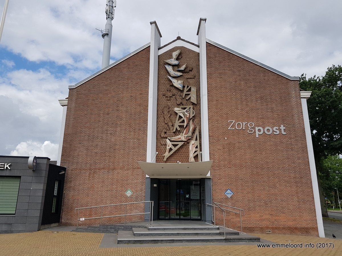 een betonreliëf van opvliegende postduiven en een zittende vrouw die telefoneert